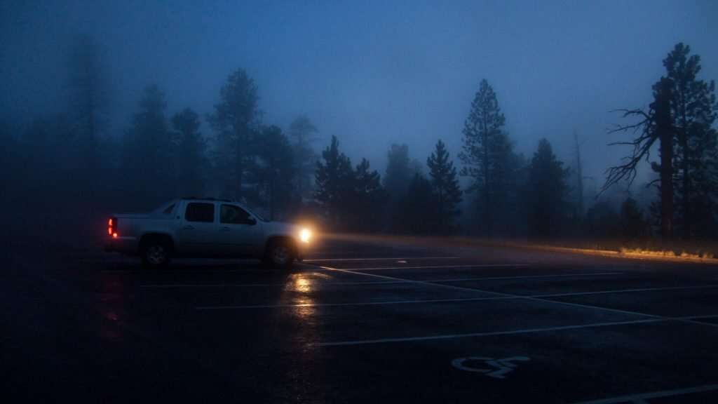Truck parked in a parking lot with fog lights on at night.