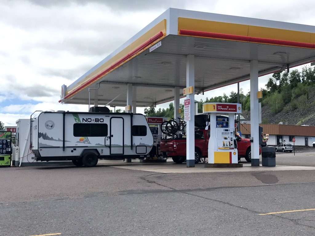 Truck with travel trailer filling up at gas station